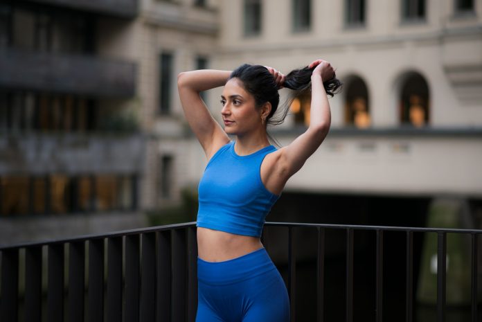 Woman in workout gear pulls her hair back.