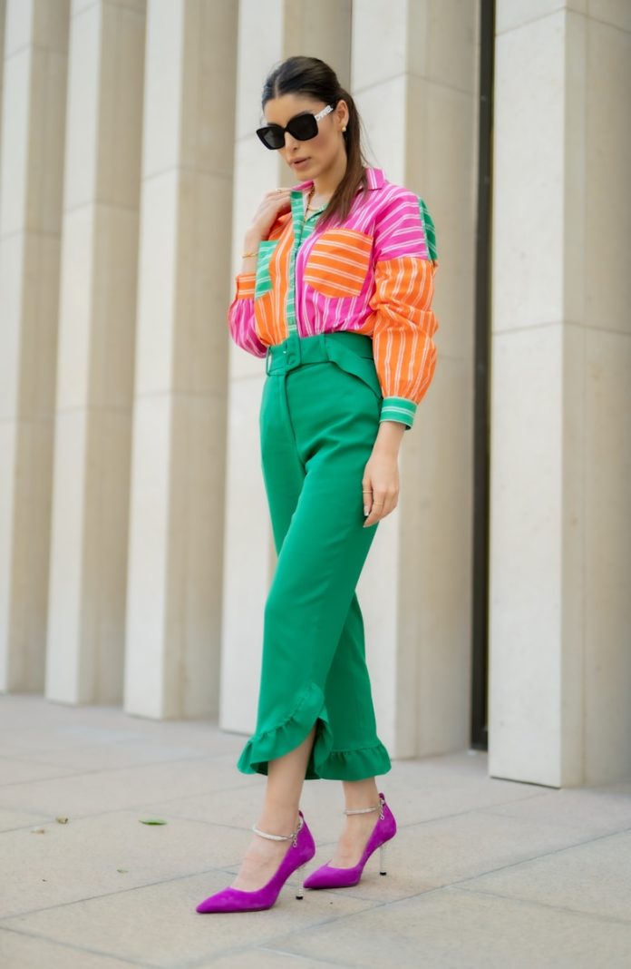 A woman in a colorful sweater and green pants